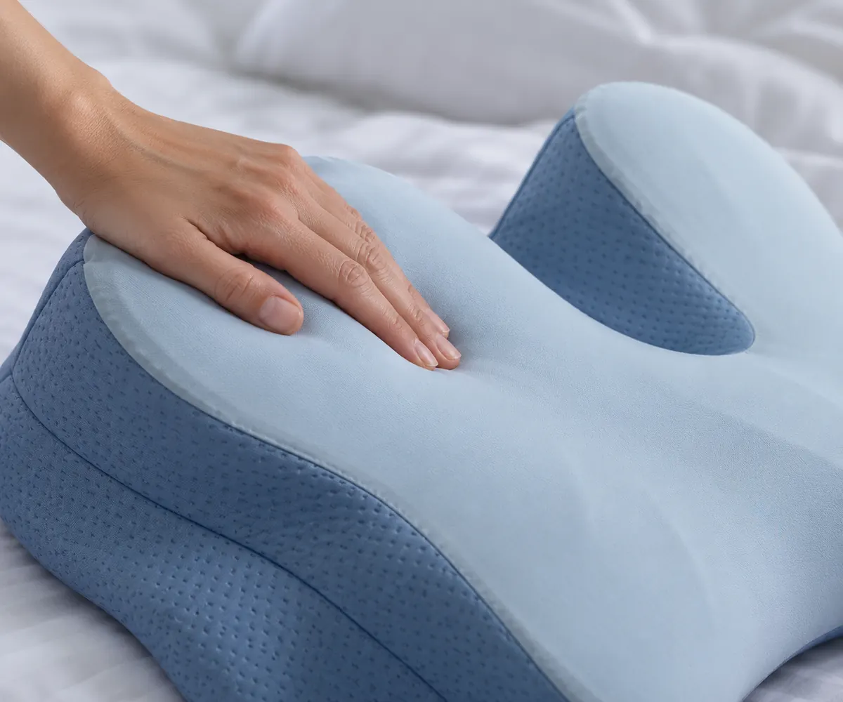 A hand pressing into the light blue memory foam pillow, leaving a slow imprint